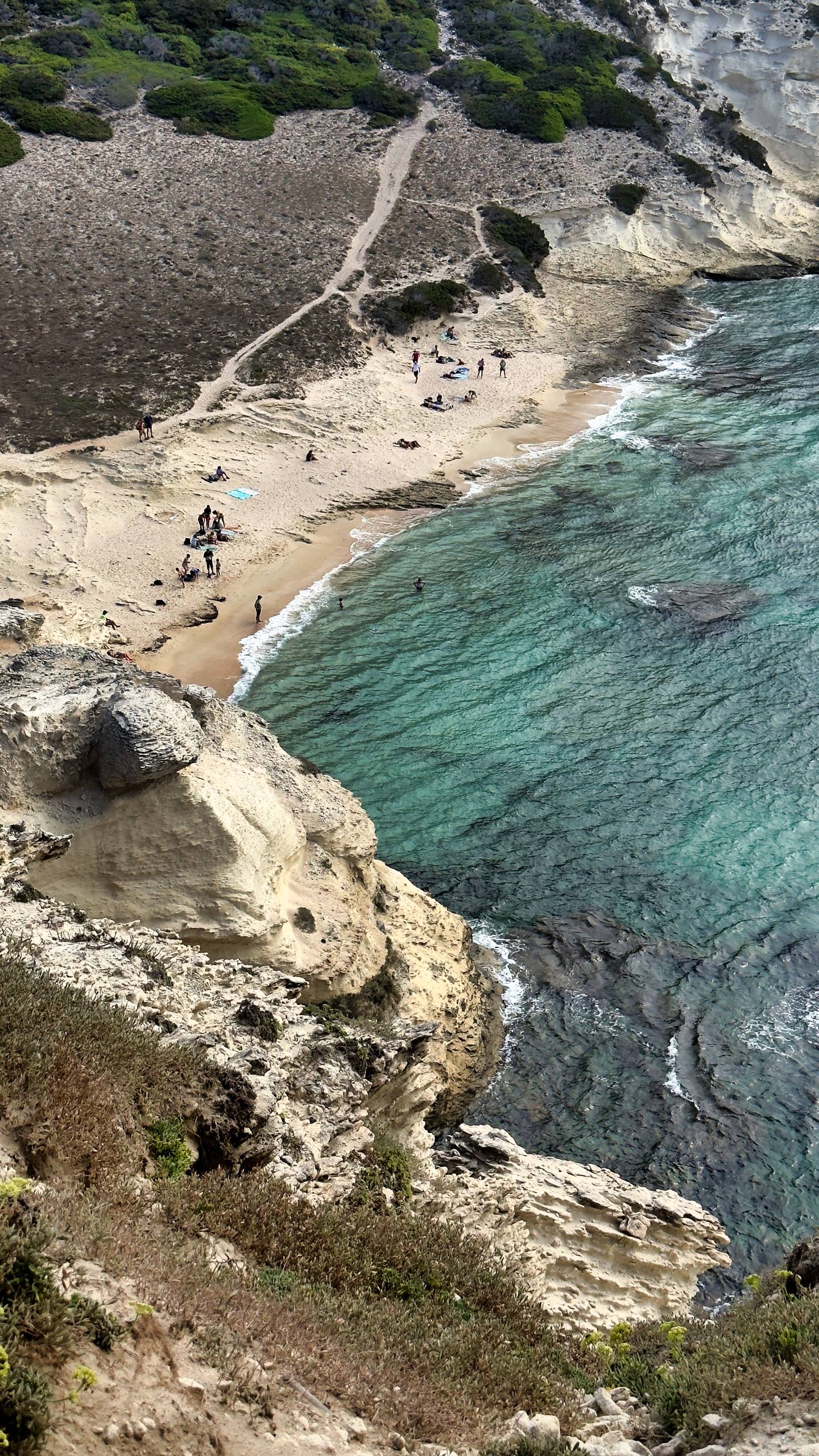 A small sandy cove with turquoise water seen from above