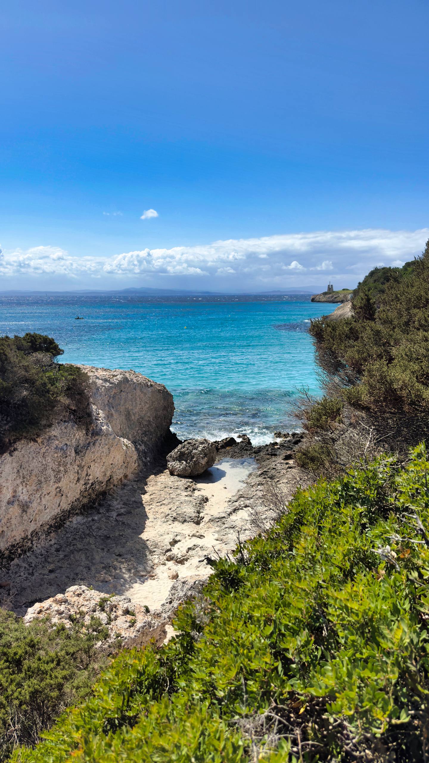 A small cove with turquoise water and a Genoese tower on the headland