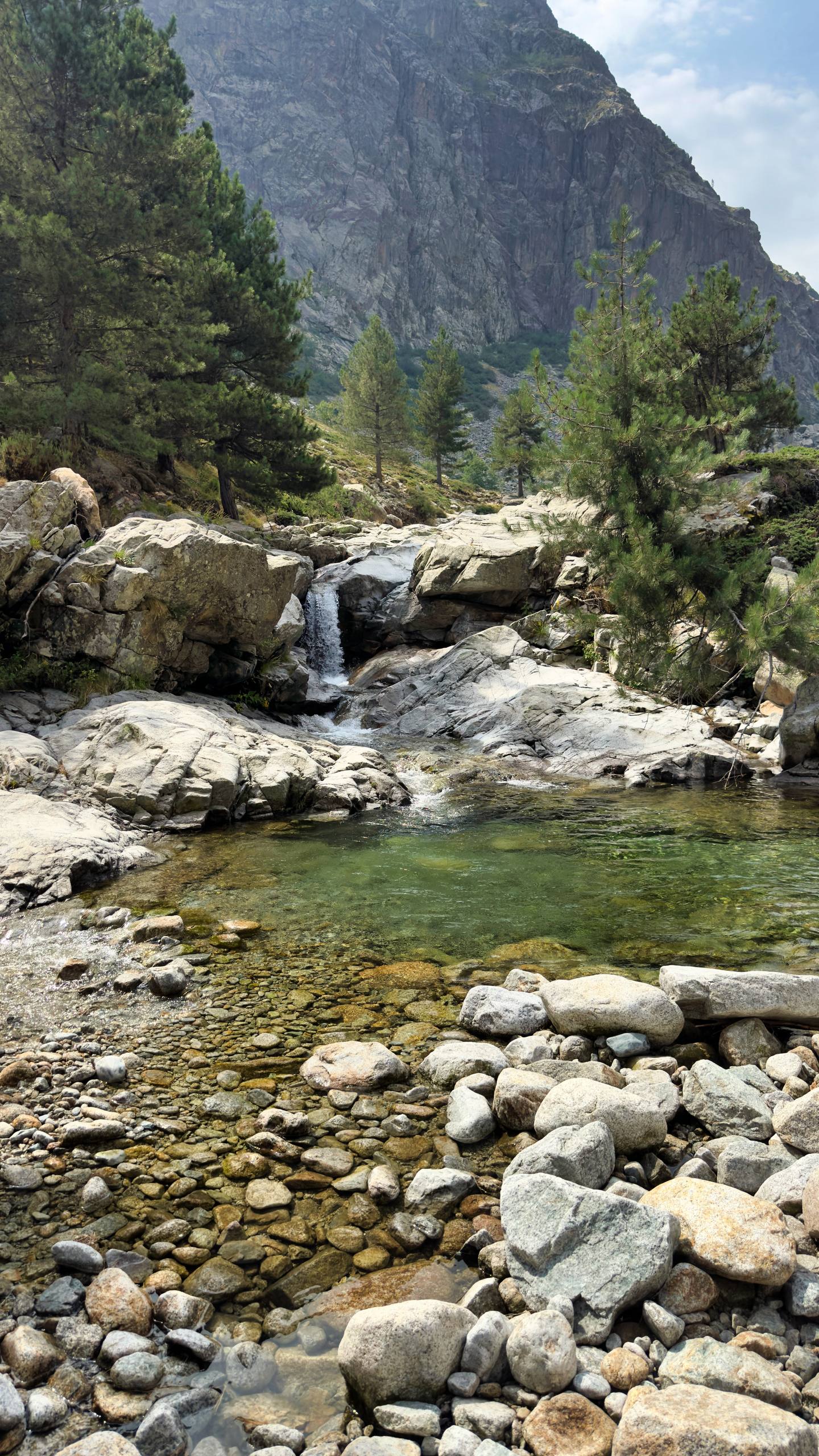 A small waterfall feeding an emerald plunge pool in a granite gorge