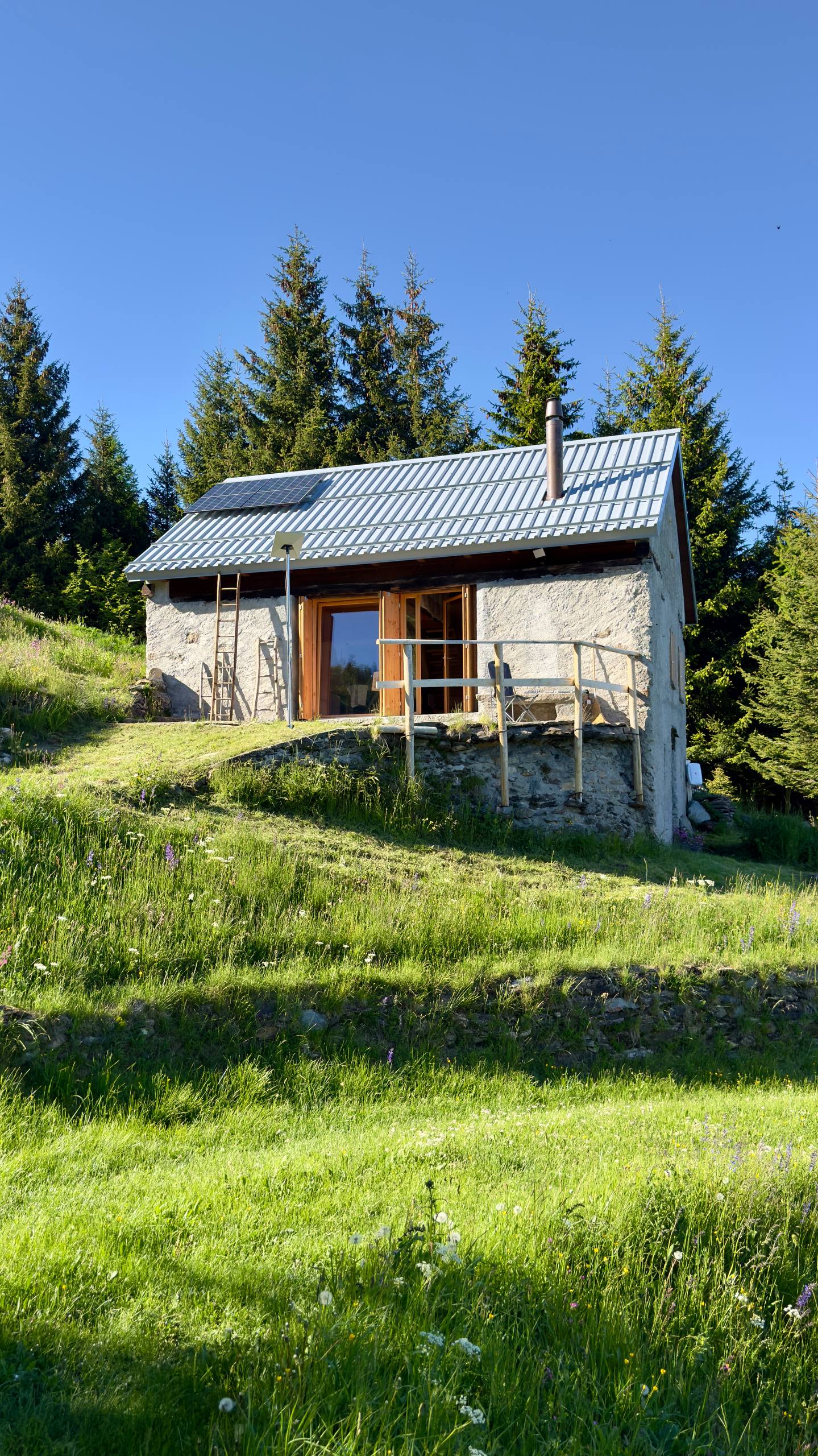 The rustico in May 2026 — new metal roof, solar panels, timber doors